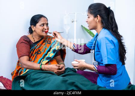 Nurse feeding sick woman to eat while on bed at nursing home - concept of support, medicare and caretaker Stock Photo