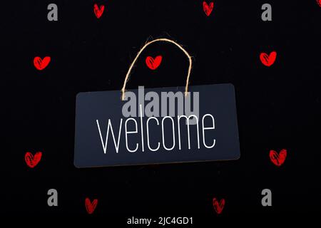 Welcome wording on black notice board with red hearts around Stock Photo