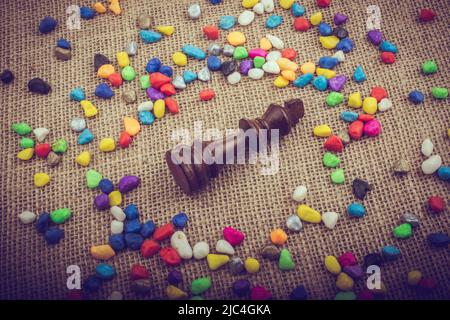 Chess king amid colorful pebbles on canvas background Stock Photo