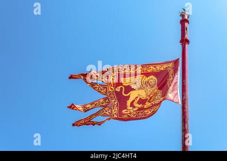 Venice, ITALY - July 22, 2020. The venetian flag is flying in the blue sky. Italian travel and patriot concept. Copy space. Stock Photo