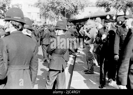 A far right National Front (NF) March, London, England, United Kingdom, surrounded by police officers, September, 1978. On the same day an Anti Nazi League march took place in London so the police were there in great numbers to keep the two marches apart and deal with any conflict between them. An image of many men in a dark uniform together, with maybe 5 non-uniformed men just about visible, hard to see the NF protesters in this phalanx of policemen; some police men had long hair (left foreground). Taken on a retro 35mm film camera on black and white film, probably Ilford FP4 film. Stock Photo