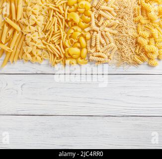 Different types and shapes of Italian pasta on white wooden background Stock Photo
