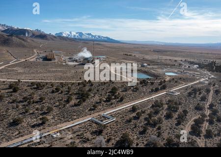 Steam rising from cooling towers at the Blundell Geothermal Power Plant in Utah.  Steam pipes run from production wells to the power plant. Stock Photo