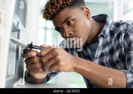 young man repairing microwave oven in kitchen Stock Photo