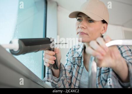 young woman worker using silicone sealant on construction site Stock Photo