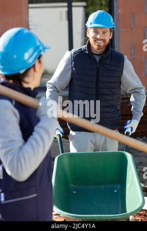 builder pushing a wheelbarrow on site Stock Photo