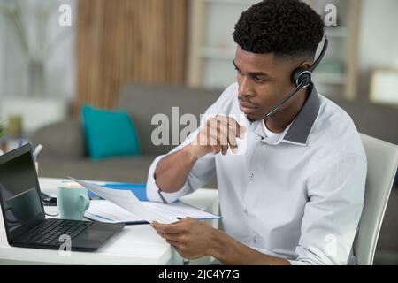 black male call centre worker looking at screen Stock Photo