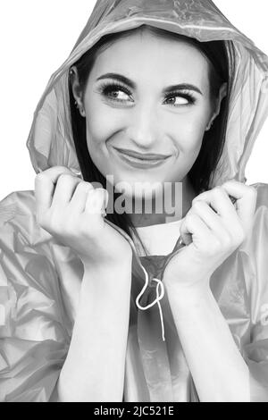 Beautiful woman black and white studio portrait. Model wearing plastic raincoat and hiding under hood and hold it with her hands. Model with smile in Stock Photo