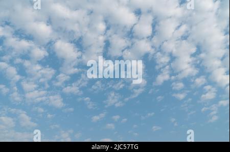 Blue sky with white patchy clouds. Also known as Altocumulus clouds. Stock Photo