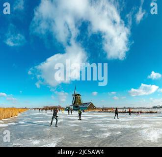 Scating on a frozen canal near a windmill *** Local Caption ***  Netherlands,windmill, water, winter, snow, ice, people, scaters,  ,Westzaan,   Noord- Stock Photo