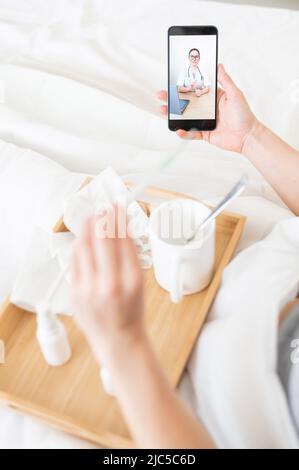 Female hands holding a phone. Remote reception at the therapist. A friendly doctor gives recommendations for treatment online. Medications and Stock Photo