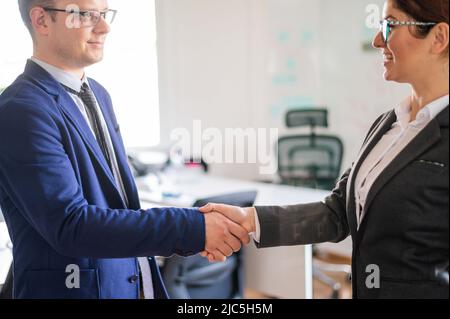 Handshake business man and woman at the conclusion of a successful transaction. Office staff in suits during a greeting. Successful job interview. Stock Photo