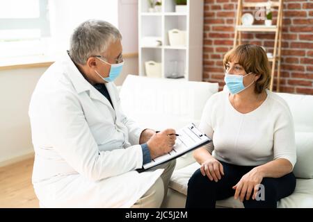 Doctor Talking To Elderly Patient At Home Stock Photo