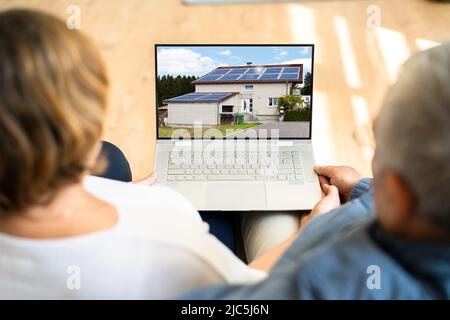 Couple Looking At House Online On Laptop At Home Stock Photo