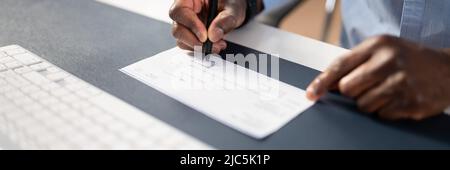 Photo Of Businessperson's Hand Signing Cheque With Pen Stock Photo
