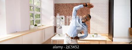 Smiling Young Businessman Doing Stretching Exercise In Office Stock Photo
