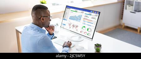 Businessman Looking At Dashboard Analyzing KPI Graph On Computer Stock Photo