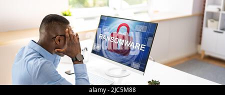 Worried Businessman Looking At Computer With Ransomware Word On The Screen At The Workplace Stock Photo