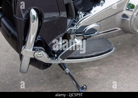 close view on chrome classic road motorcycle on asphalt parking at spring day - close side view on footboard Stock Photo