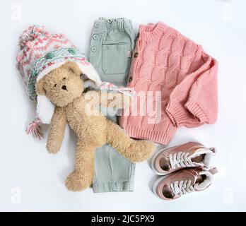 Child's winter clothes set. Knitted sweater,pants, hat and toy top view on white background. fashion kid's warm clothing flat lay. Autumn baby's outll Stock Photo