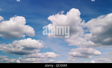 Fluffy clouds on the blue sky. Drone panning. Stock Photo