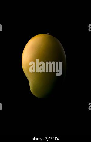 ripe mango, isolated on black background, closeup of edible stone fruit Stock Photo