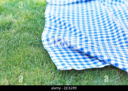 Blue checkered towel on grass,gingham napking outdoor.Product advertisement display.Green grass  picnic cloth top view background.Food promotion desig Stock Photo