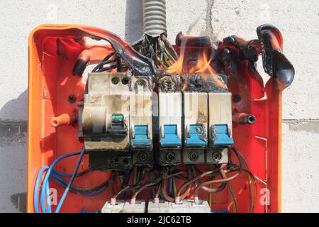 Burning switchboard from overload or short circuit on the wall Stock Photo