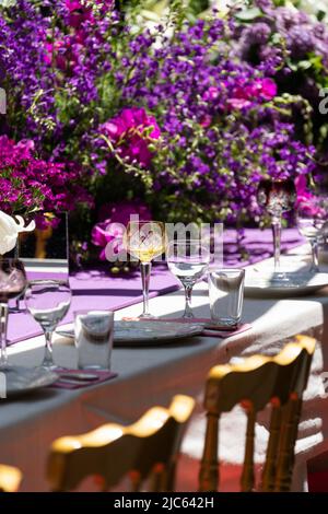 Decoration festival table with purple and white flowers and glassware on tablecloth. Selective focus Stock Photo