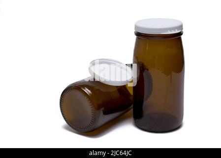 Close up of two small brown milk or yogurt glass bottles with plastic lids on white background Stock Photo