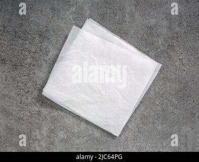 White crumpled square paper,napkin top view on grey stone table.Food advertisement design.Kitchen paper flat lay. Stock Photo