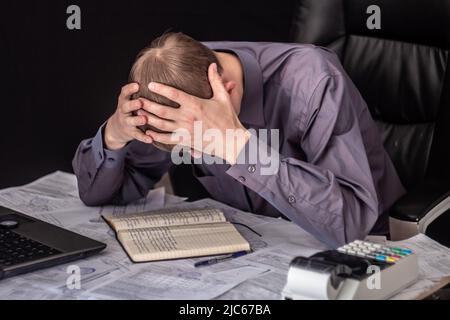 The state of crisis, failure and depression. Work with documents. Frustrated guy at the Desk with documents. Problems with documents, debts on loans a Stock Photo