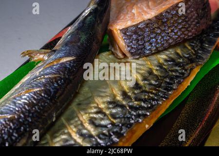 Closeup grilled Japanese Sanma fish (Pacific saury), Shiojake (salted salmon) and Saba No Shioyaki (salted mackerel) in a plastic food tray. Stock Photo