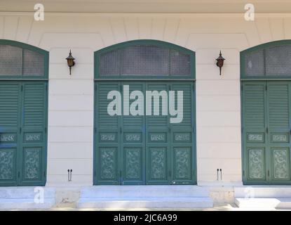 dusty white ancient building facade with beautiful green wooden   windows. Stock Photo