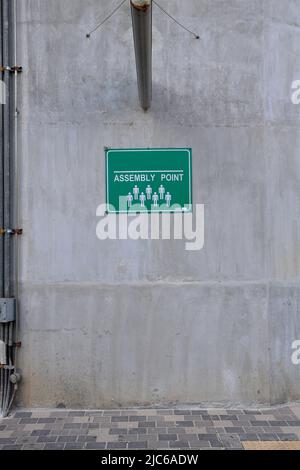 assembly point sign board on concrete wall Stock Photo