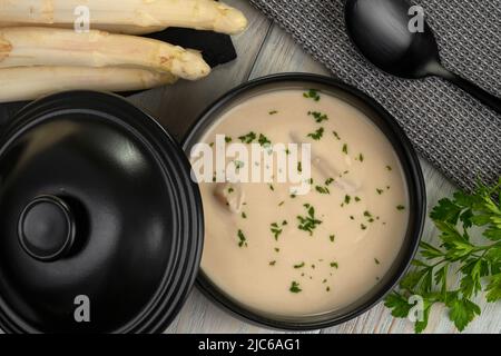Delicious white asparagus cream soup on wooden background Stock Photo