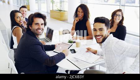 Cropped shot of a group of businesspeople sitting around the boardroom table during a meeting Stock Photo