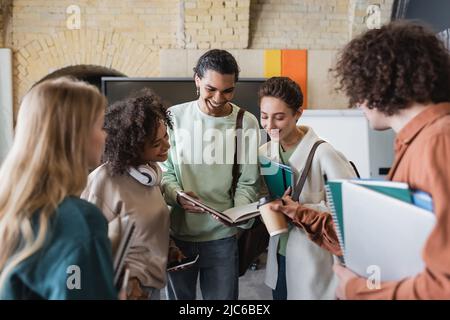 happy african american student showing copybook to multiethnic classmates Stock Photo