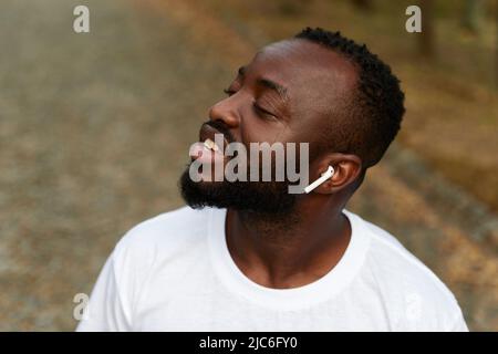 Happy young adult african american man walking in the park wearing headphones Stock Photo