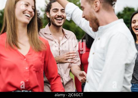 Multiethnic group of friends having fun dancing together outdoor during summer vacations - Focus on center man face Stock Photo