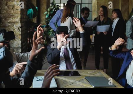 Diverse business people working with virtual reality headsets inside coworking office - Focus on senior man face Stock Photo