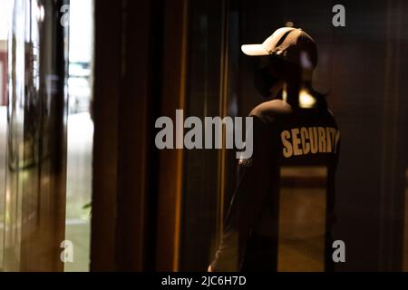 Female security guard walking through an automated revolving curved sliding door to patrol a commercial area Stock Photo