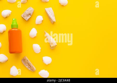 Top view of seashells and sunscreen in bottle on yellow background Stock Photo