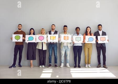 Group of people holding white sheets of paper with empty colored speech bubbles on them. Stock Photo