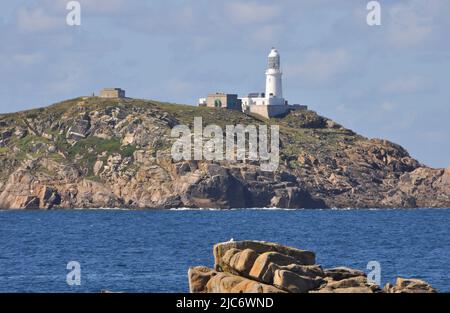 Round Island in the Isles of Scilly archipelago with its Lighthouse perched on the top of the rugged granite outcrop, from coast path winding through Stock Photo