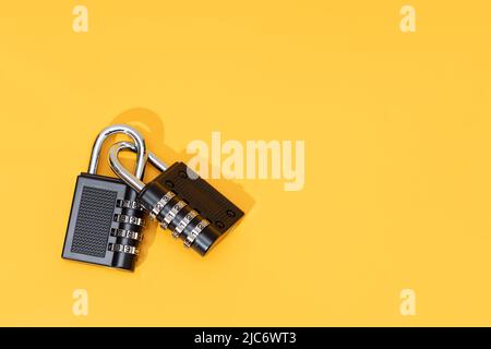 Two padlocks linked together isolated on yellow background. Copy space. Top view Stock Photo
