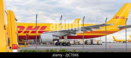 Schkeuditz, Germany - 29th May, 2022 - Many courier van against cargo planes parked on Leipzig Halle airport terminal apron for loading distribution Stock Photo