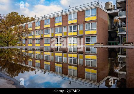 A housing estate in London, apartments reflect on a puddle on top or garages. Stock Photo