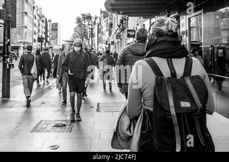 Commuters walking along Tottenham Court Road in London during the morning rush hour - Black and white street photography.