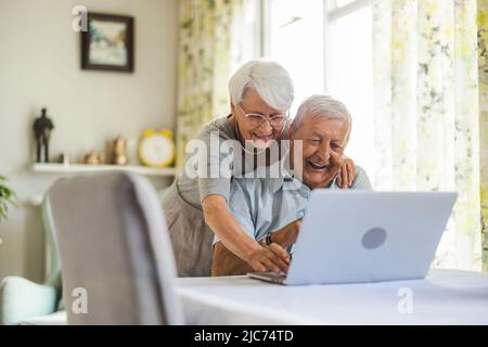 Happy senior couple using laptop at home Stock Photo